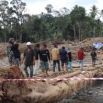 FOTO 15 Des_Warga melintasi jembatan darurat di Desa Garoga, Kecamatan Batang Toru, Tapanuli Selatan.