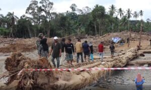 FOTO 15 Des_Warga melintasi jembatan darurat di Desa Garoga, Kecamatan Batang Toru, Tapanuli Selatan.